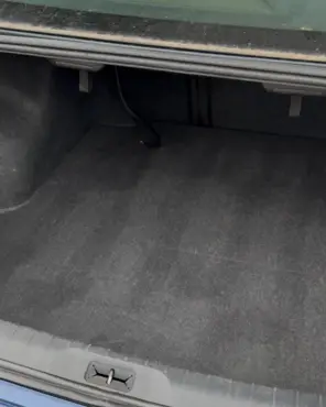 The same sedan trunk emptied, vacuumed and the carpet lifted clean