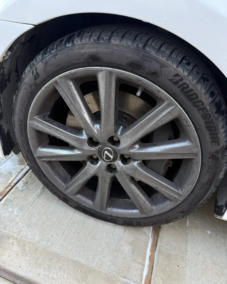 Lexus alloy wheel coated in brake dust and road grime, tire wall dull and brown
