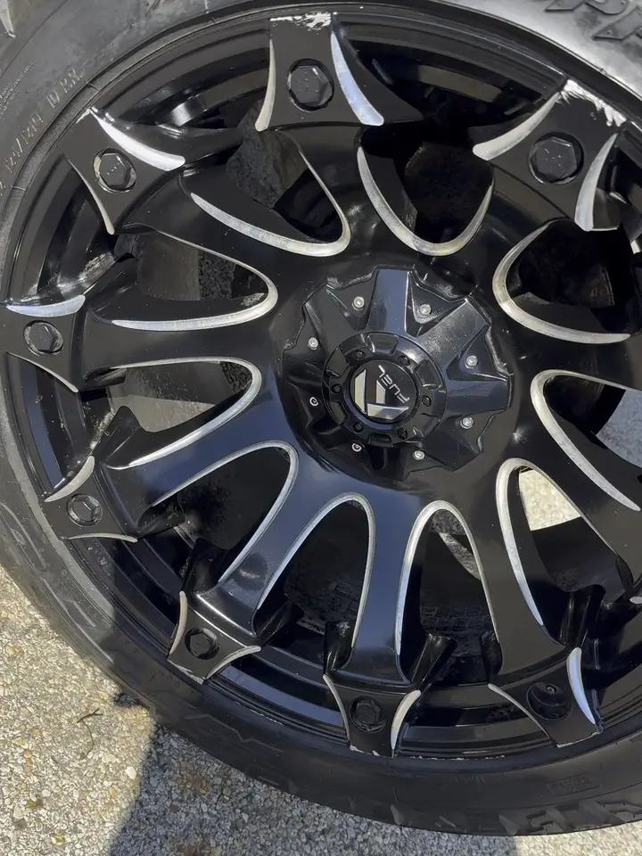 Black aftermarket alloy wheel and off-road tire on a blue Toyota Tundra, cleaned and the tire dressed